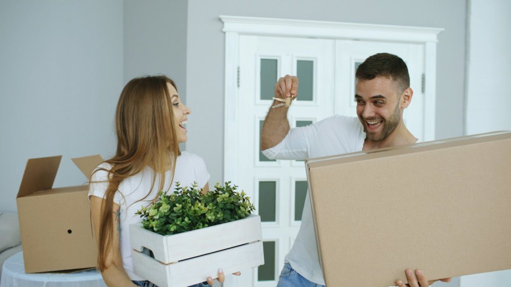 Couple carrying boxes into their new home